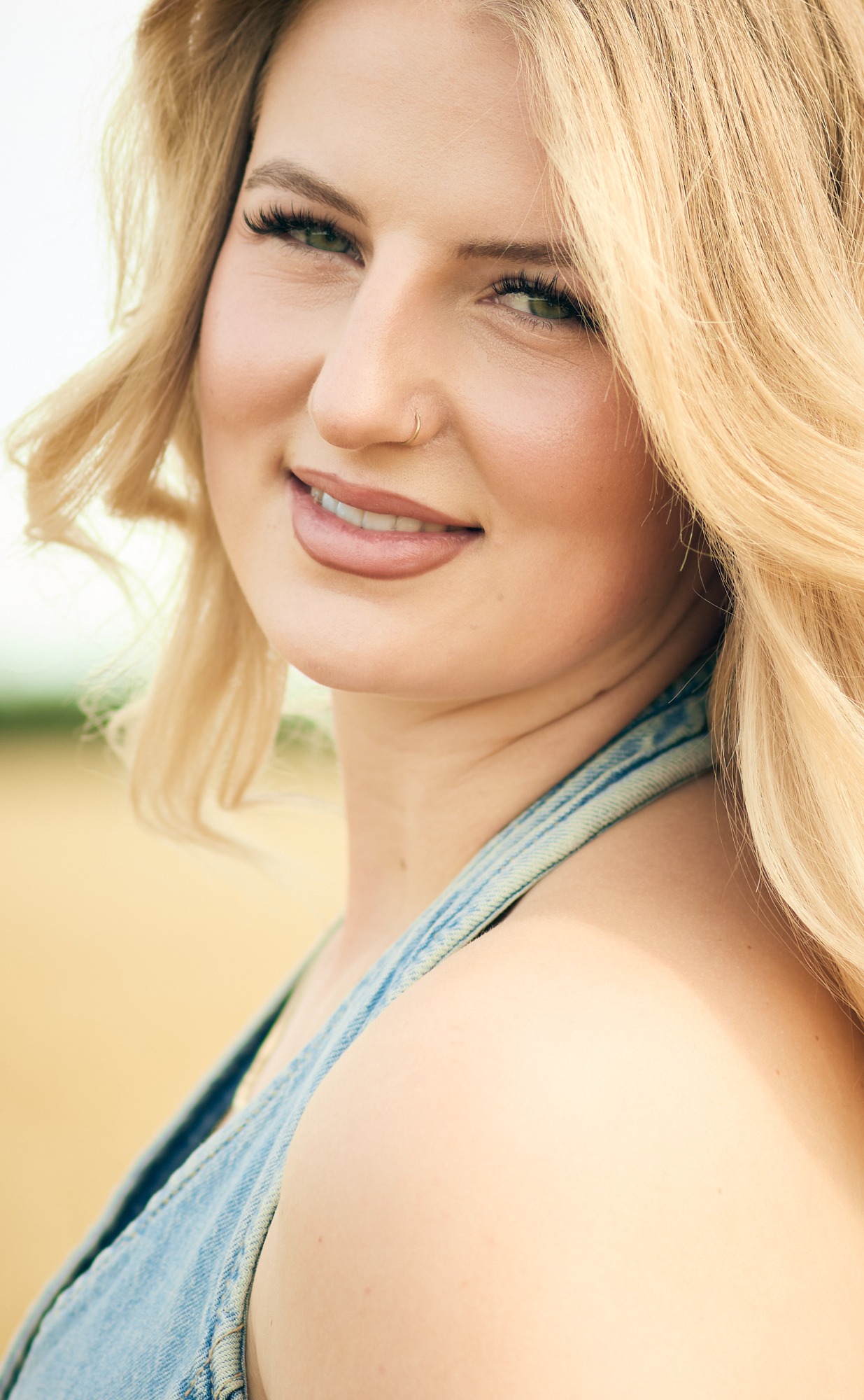 Porträt einer lächelnden Frau mit blonden Haaren in einem Feld.