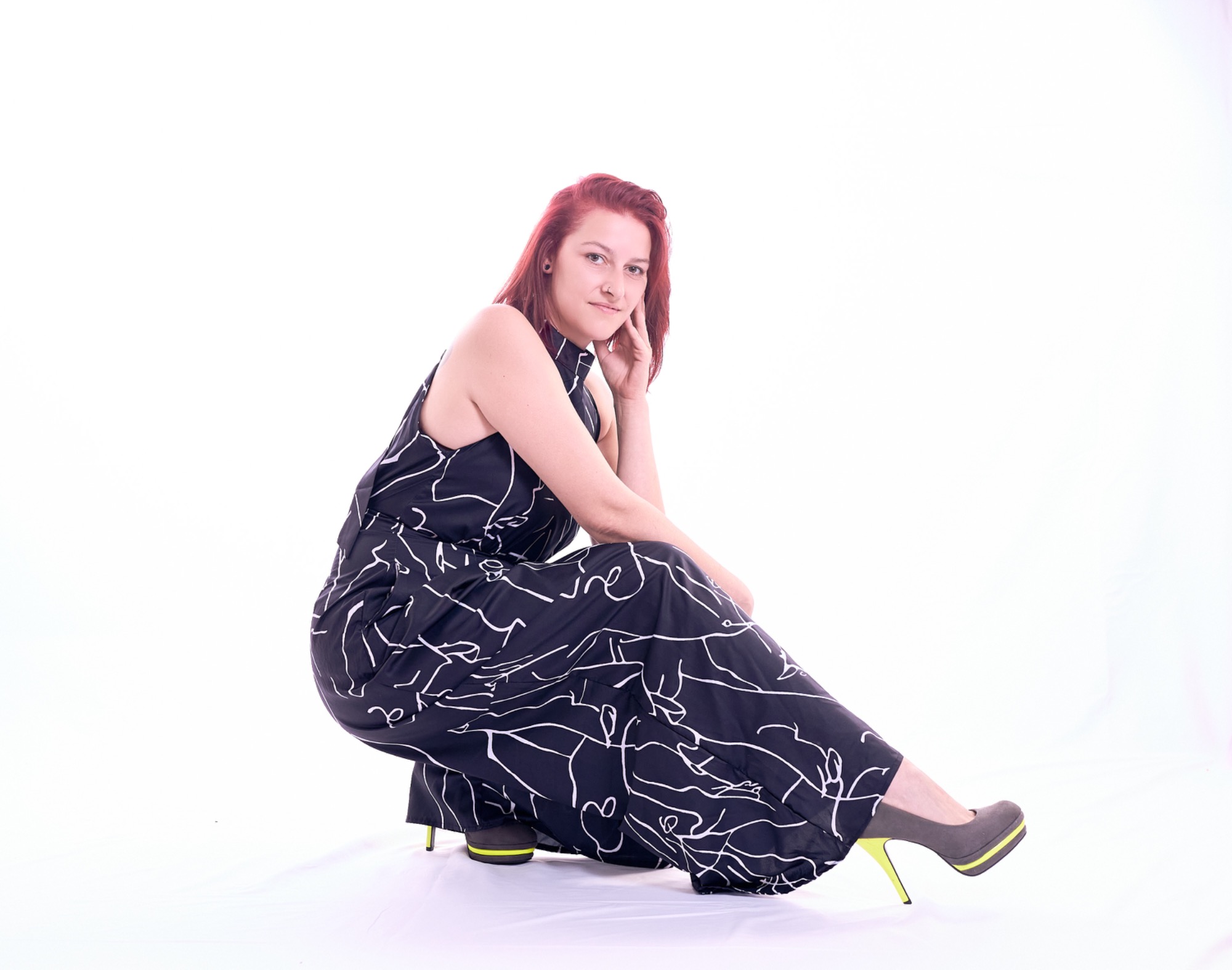 Frau mit rotem Haar in black-and-white-hose und hohen Schuhen sitzt nachdenklich.